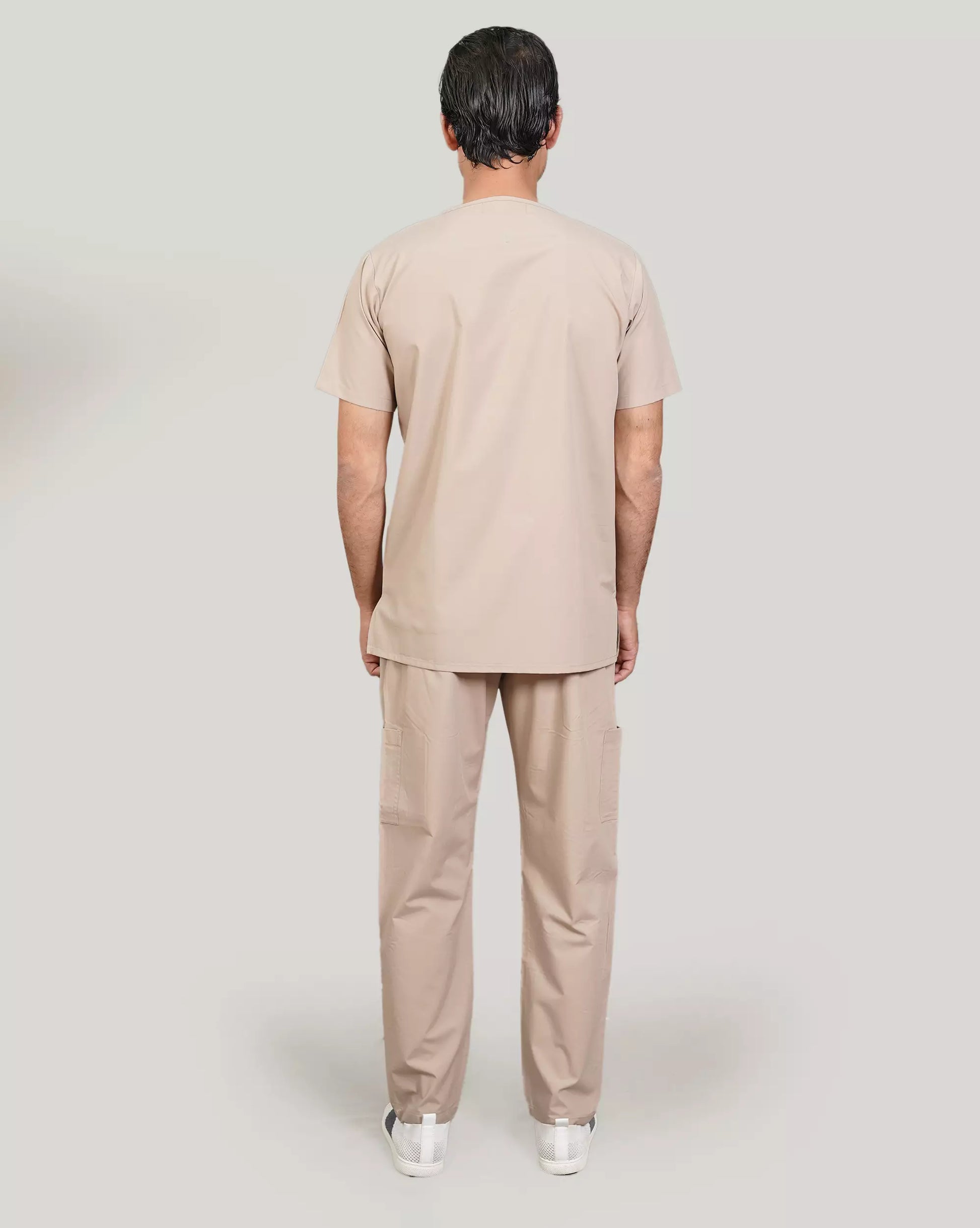 Rear view of a male medical professional in a beige Medfit men's scrub set, showcasing the relaxed fit and uniform design for medical environments.