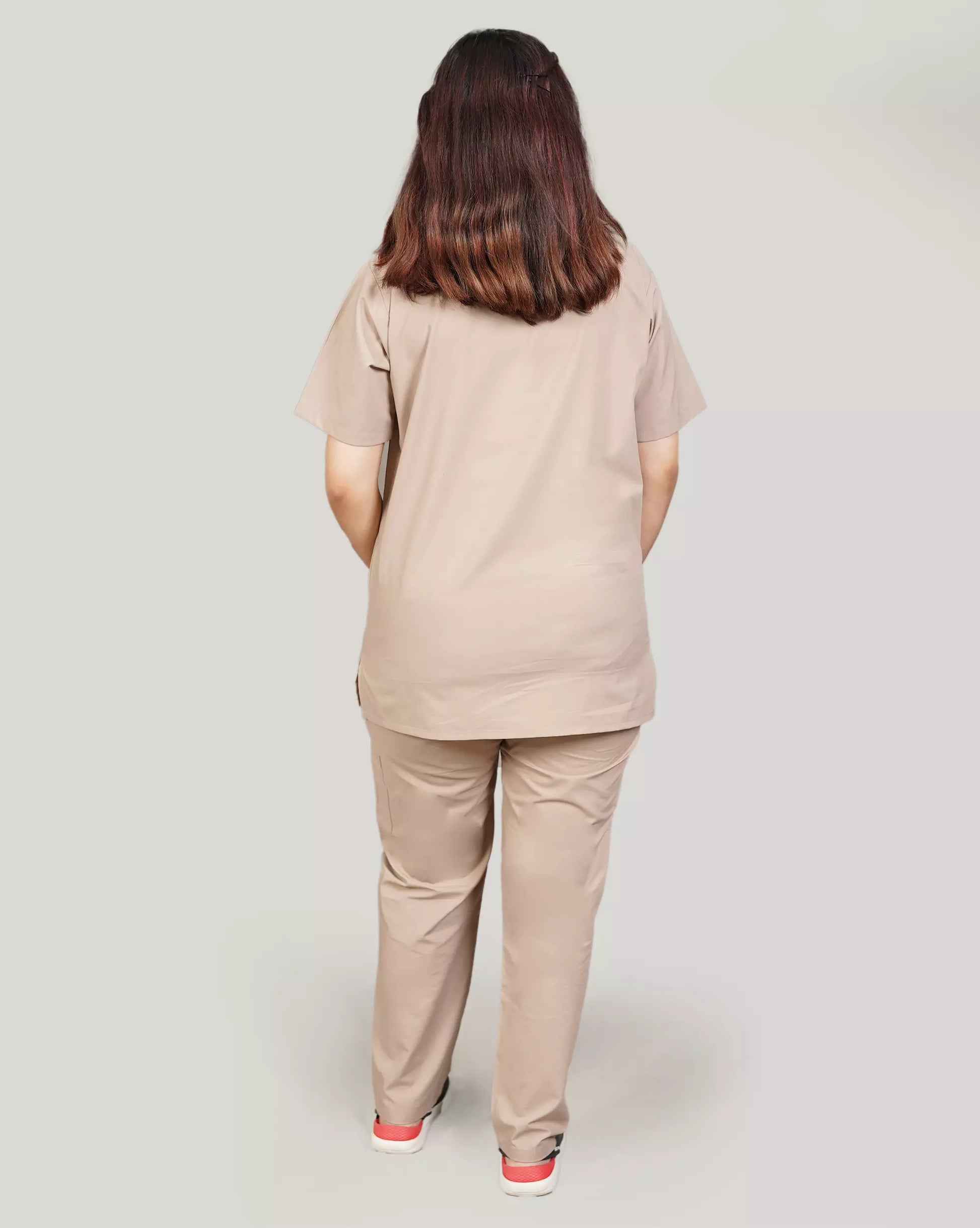 Rear view of a female medical professional in a beige Medfit unisex scrub set, showcasing the relaxed fit and durable fabric for demanding healthcare environments.