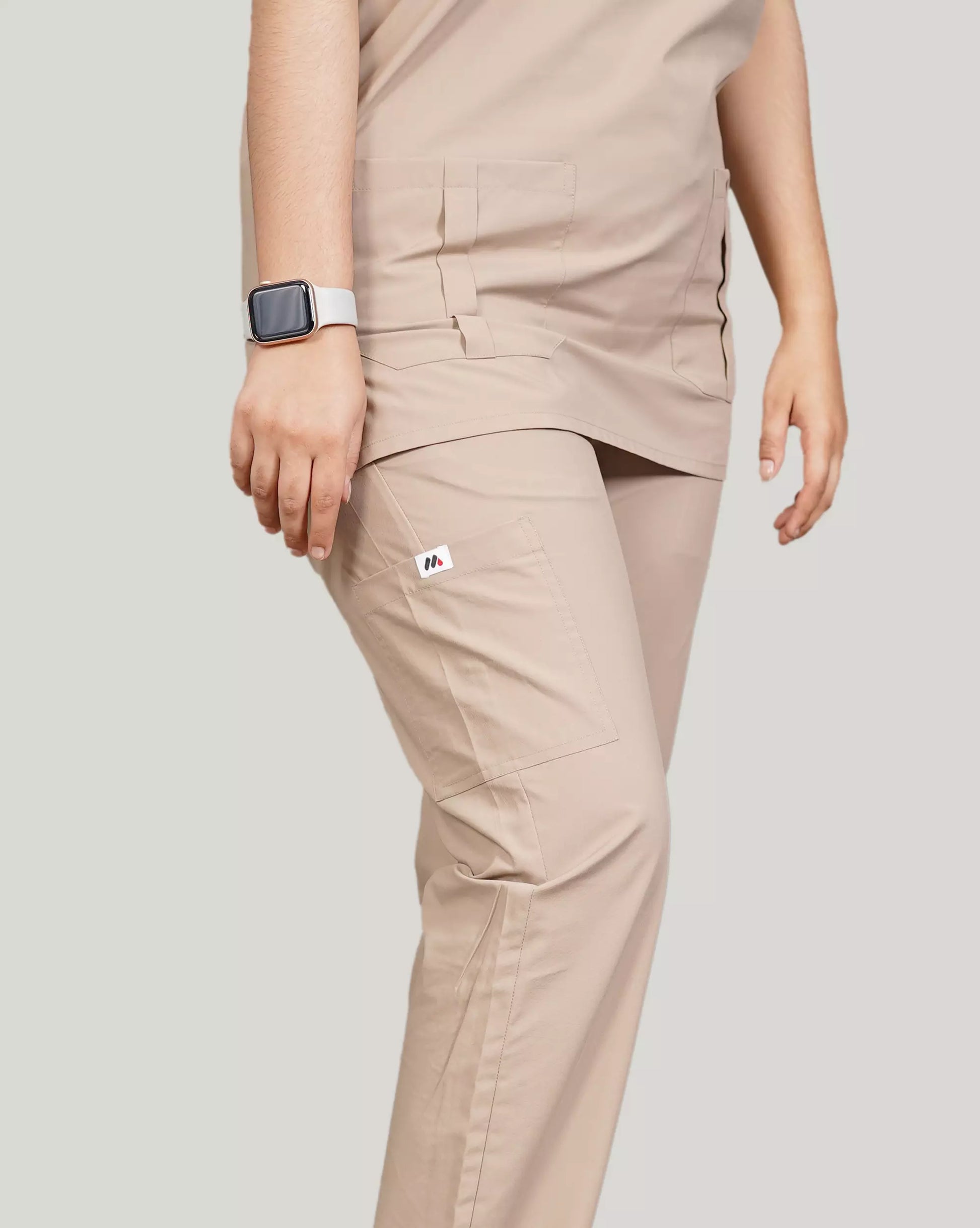 Detail shot of beige Medfit unisex scrub pants, featuring a practical side pocket and the Medfit logo, designed for comfort and functionality in medical settings.