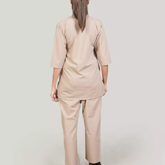 Person wearing a beige medical scrub set on a plain background