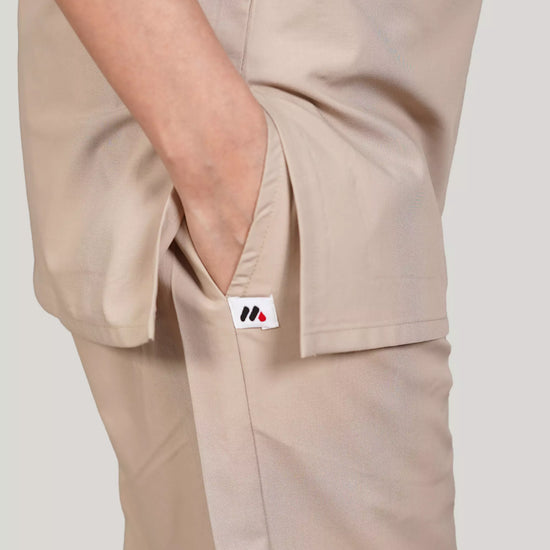Beige pants with a close-up of the pocket on a plain background.