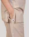 Beige pants with a close-up of the pocket on a plain background.