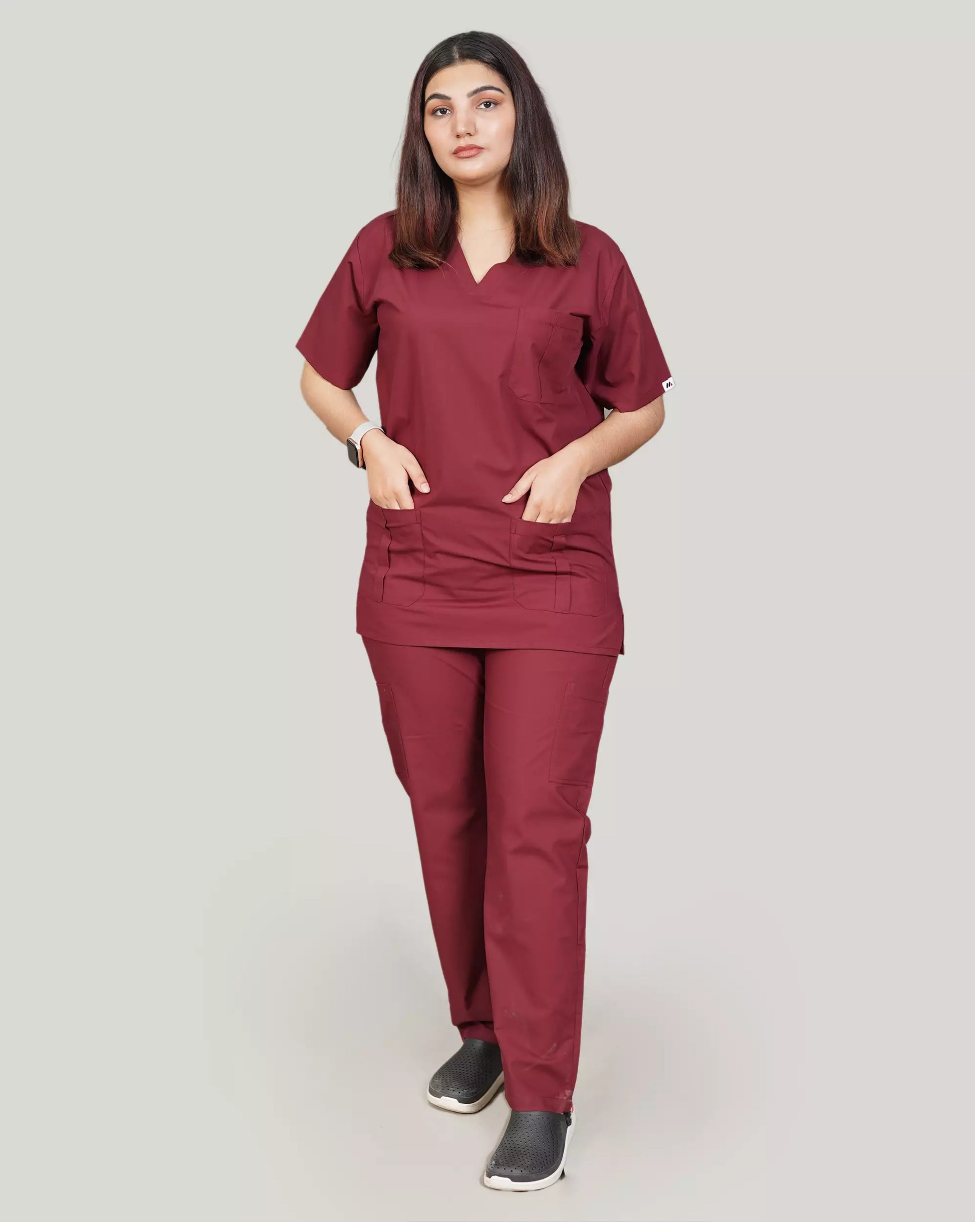 Full-body front view of a confident female medical professional in a complete burgundy Medfit unisex scrub set, designed for style and durability in healthcare environments.