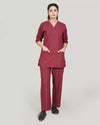 Person wearing a burgundy medical scrub set on a plain background