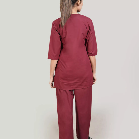 Person wearing a burgundy scrub set on a plain background