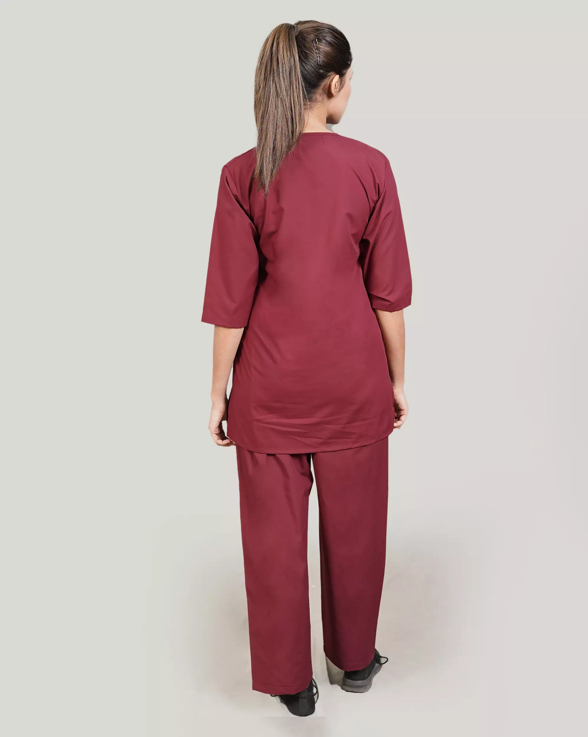 Person wearing a burgundy scrub set on a plain background