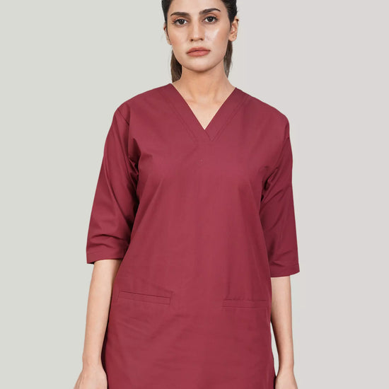 Woman wearing a maroon scrub set against a plain background