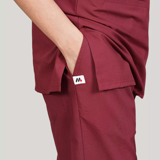 Maroon scrub pants with a pocket on a plain background