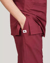 Maroon scrub pants with a pocket on a plain background