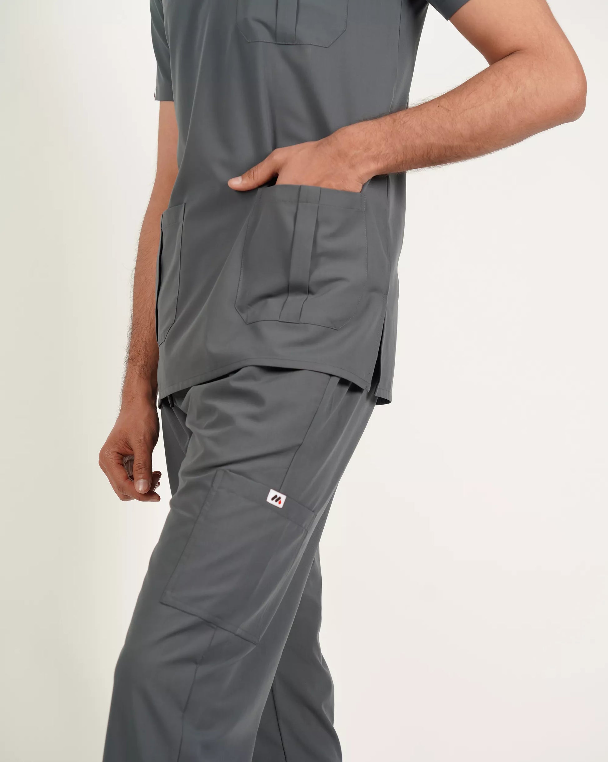 Close-up of a hand inserting a smartphone into the pocket of charcoal grey Medfit men's scrub pants, showcasing practical storage and the brand's quality for healthcare professionals.
