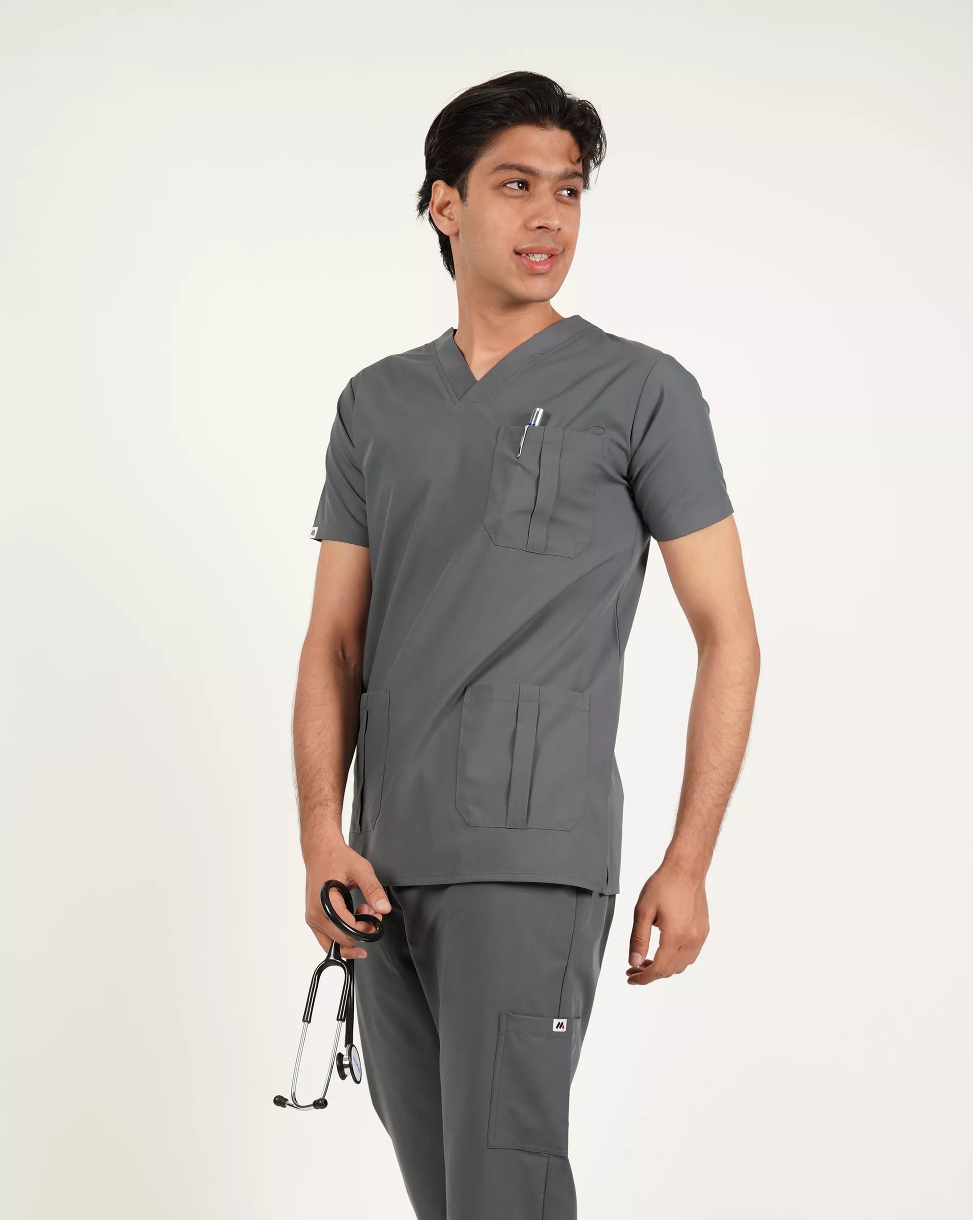 Side profile of a male medical professional in a charcoal grey Medfit men's scrub top, featuring a chest pocket and the Medfit logo on the sleeve, ideal for healthcare uniforms.