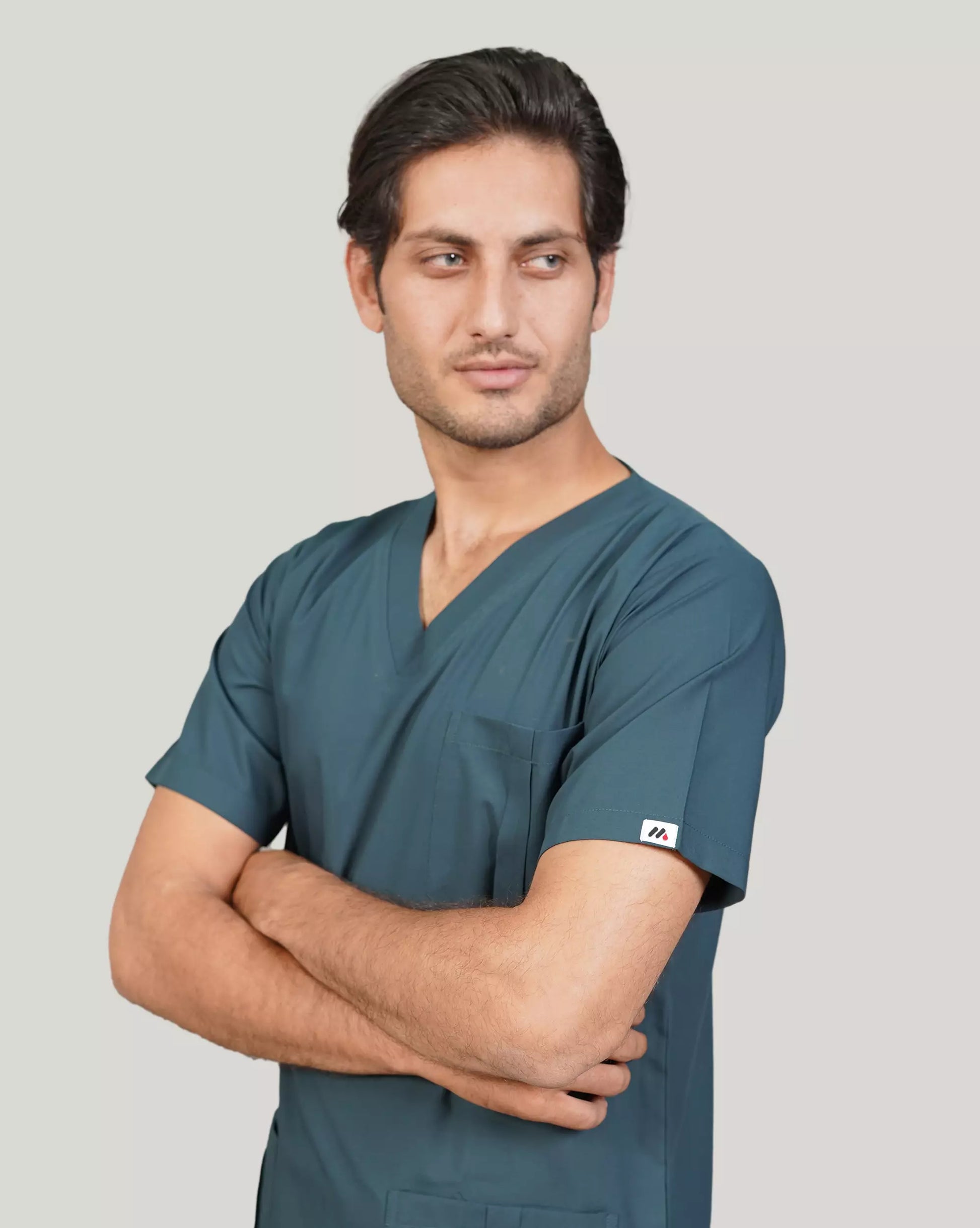 Male medical professional in an emerald green Medfit men's scrub top with crossed arms, highlighting a confident and professional look.
