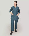 A woman doctor wearing a teal medical scrub set on a plain background