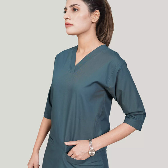 Woman wearing a teal dress against a plain background