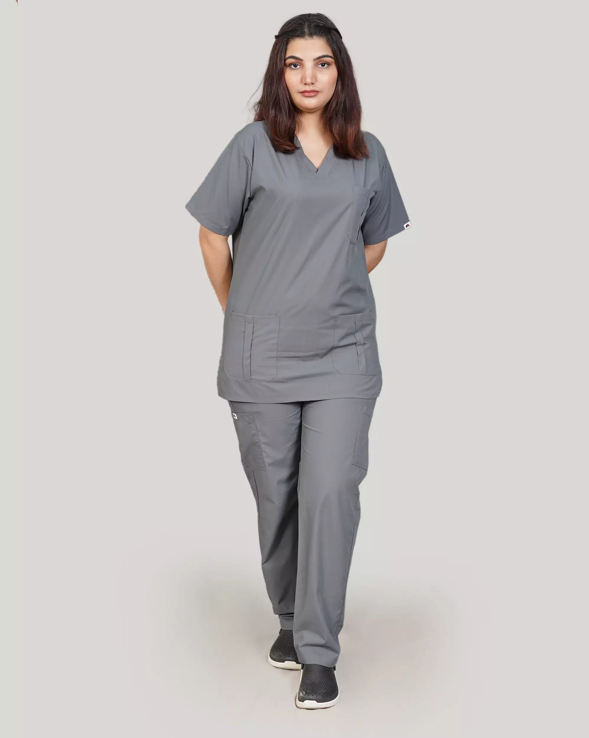 Full-body shot of a confident female medical professional in a complete basic grey Medfit unisex scrub set, emphasizing comfortable and professional medical attire.