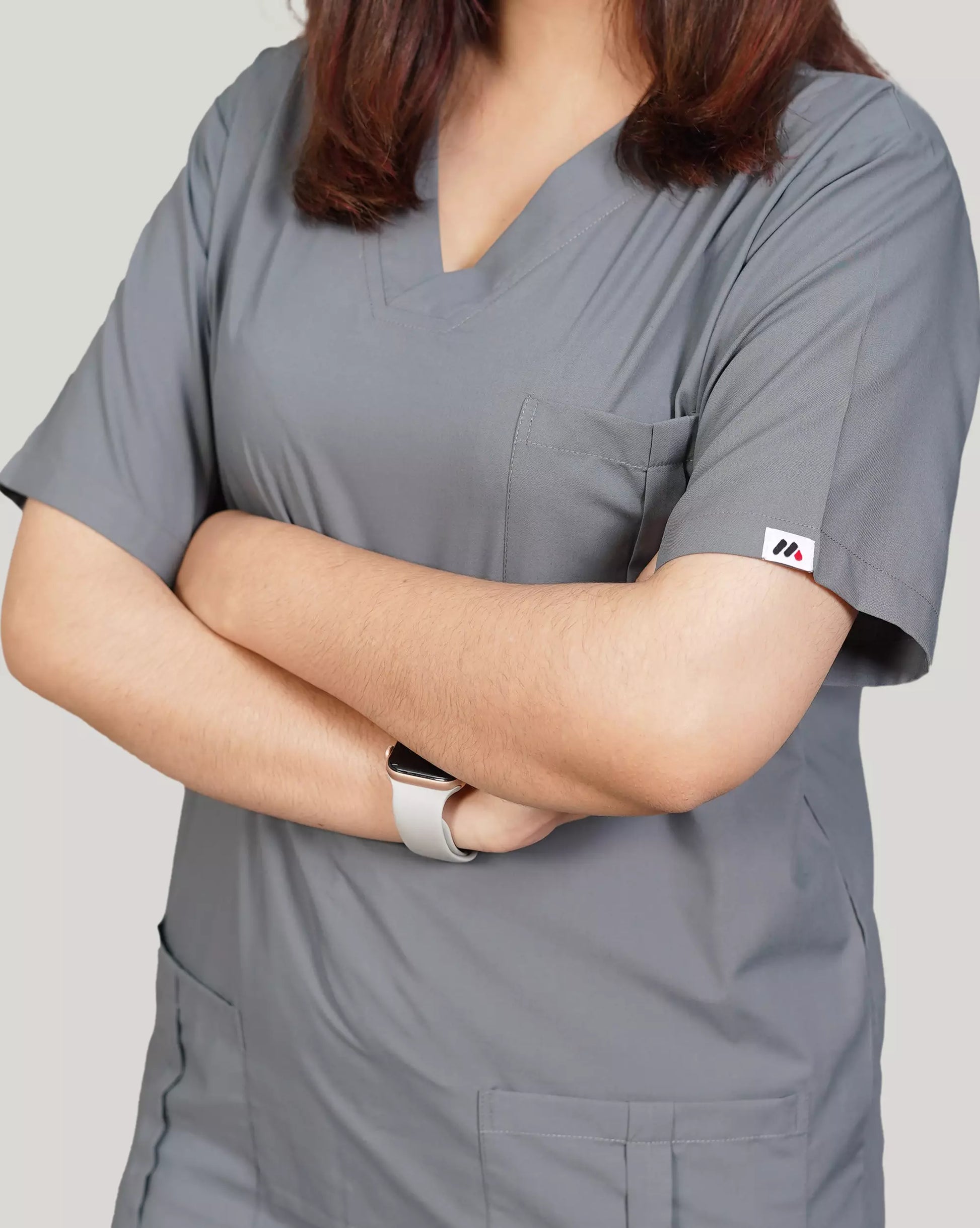Close-up of a healthcare professional in a comfortable basic grey Medfit unisex scrub top, highlighting the durable fabric and Medfit logo on the sleeve.