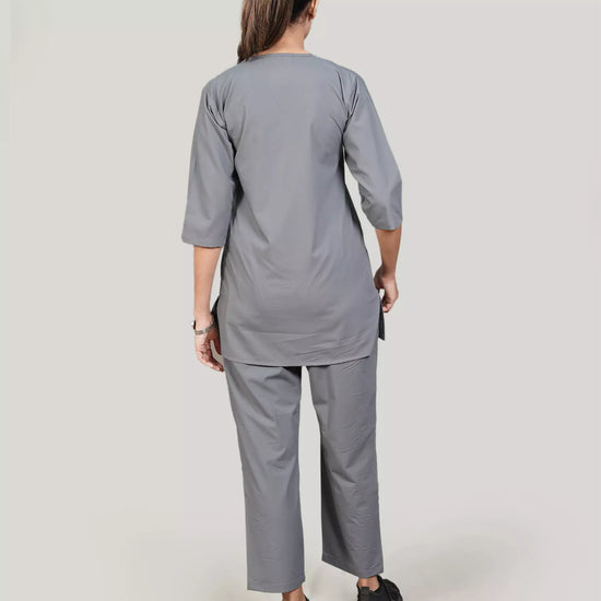 Person wearing a gray medical scrub set on a plain background