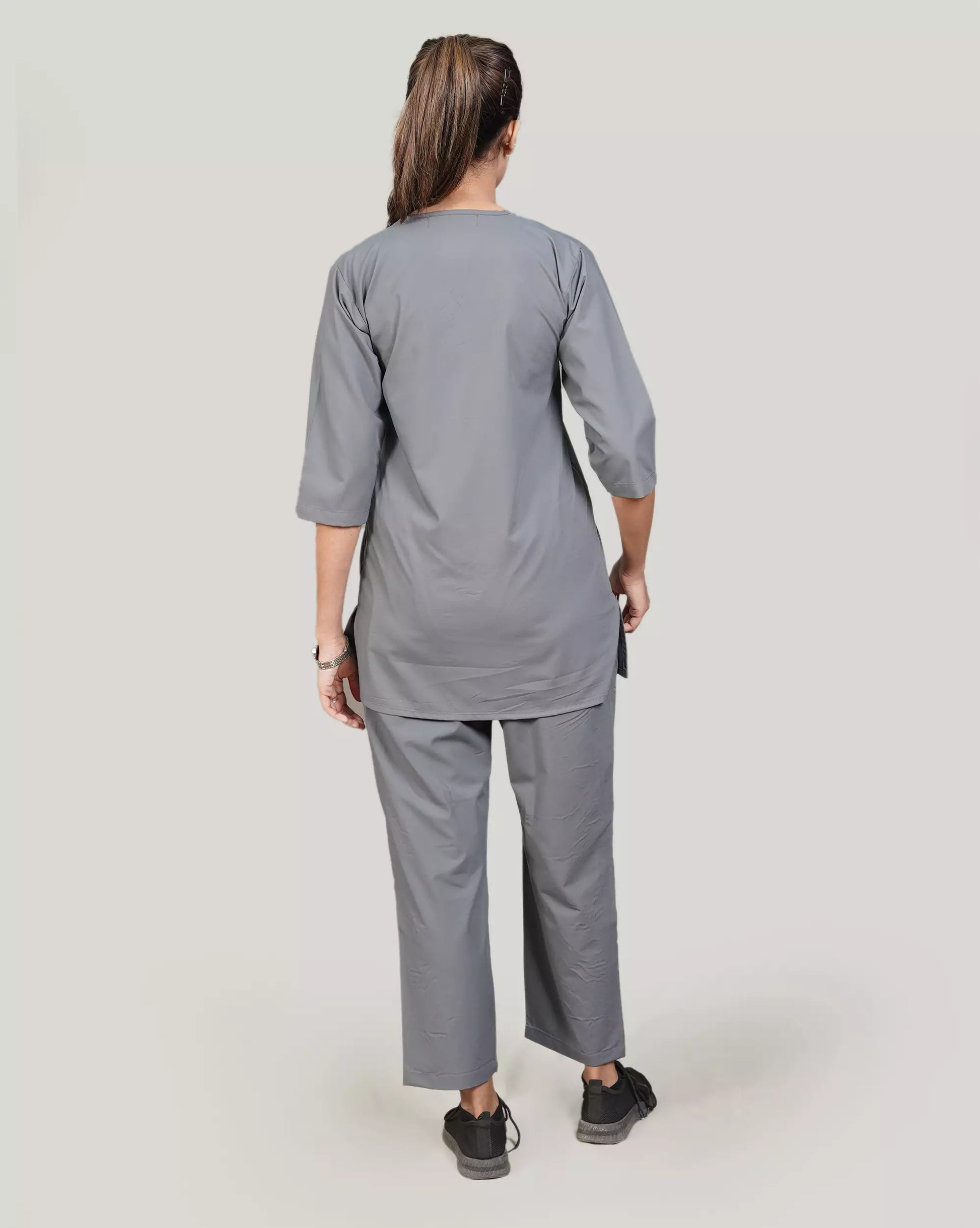 Person wearing a gray medical scrub set on a plain background
