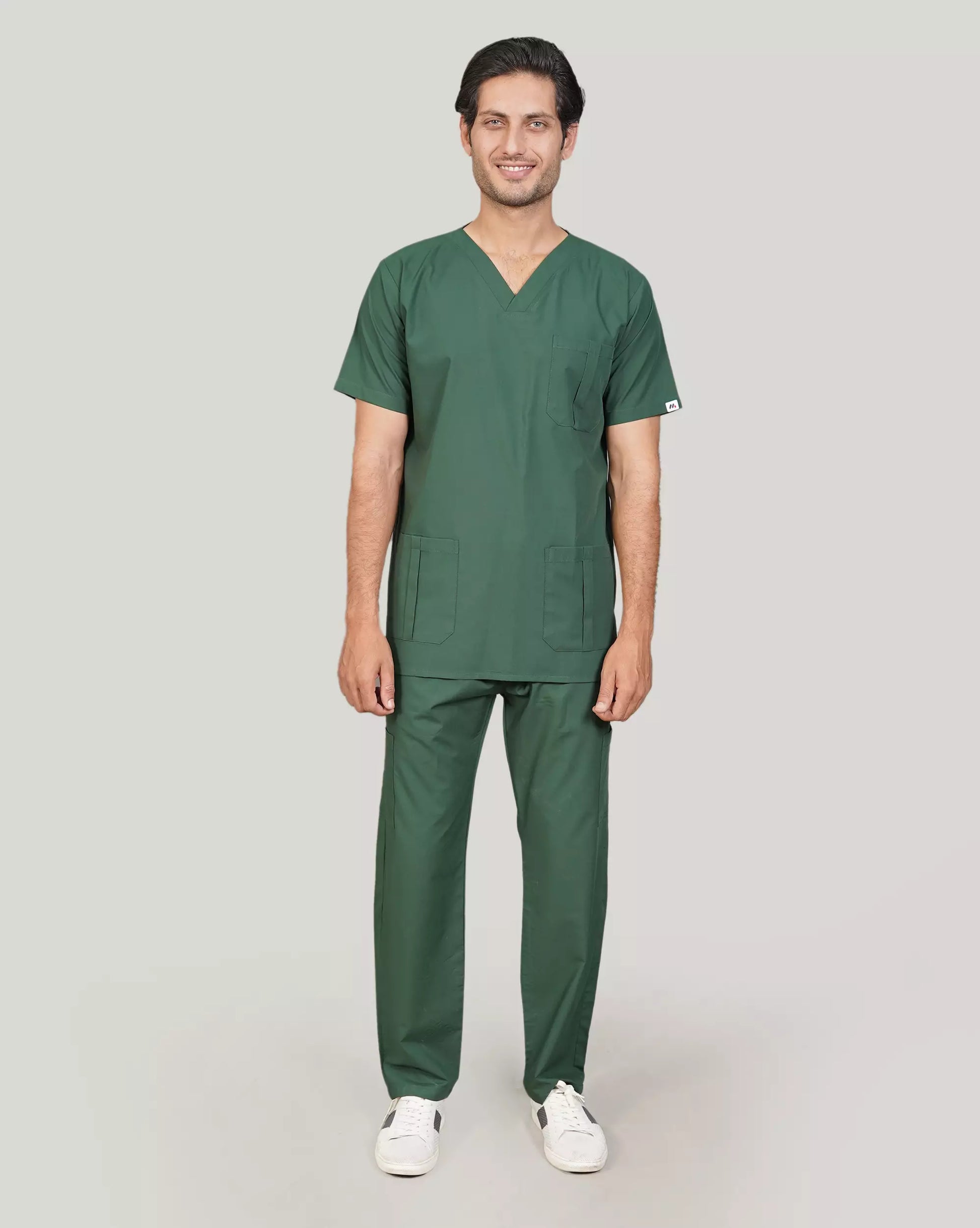 Full-body shot of a smiling male medical professional in a complete hunter green Medfit men's scrub set, showcasing professional and comfortable healthcare attire.