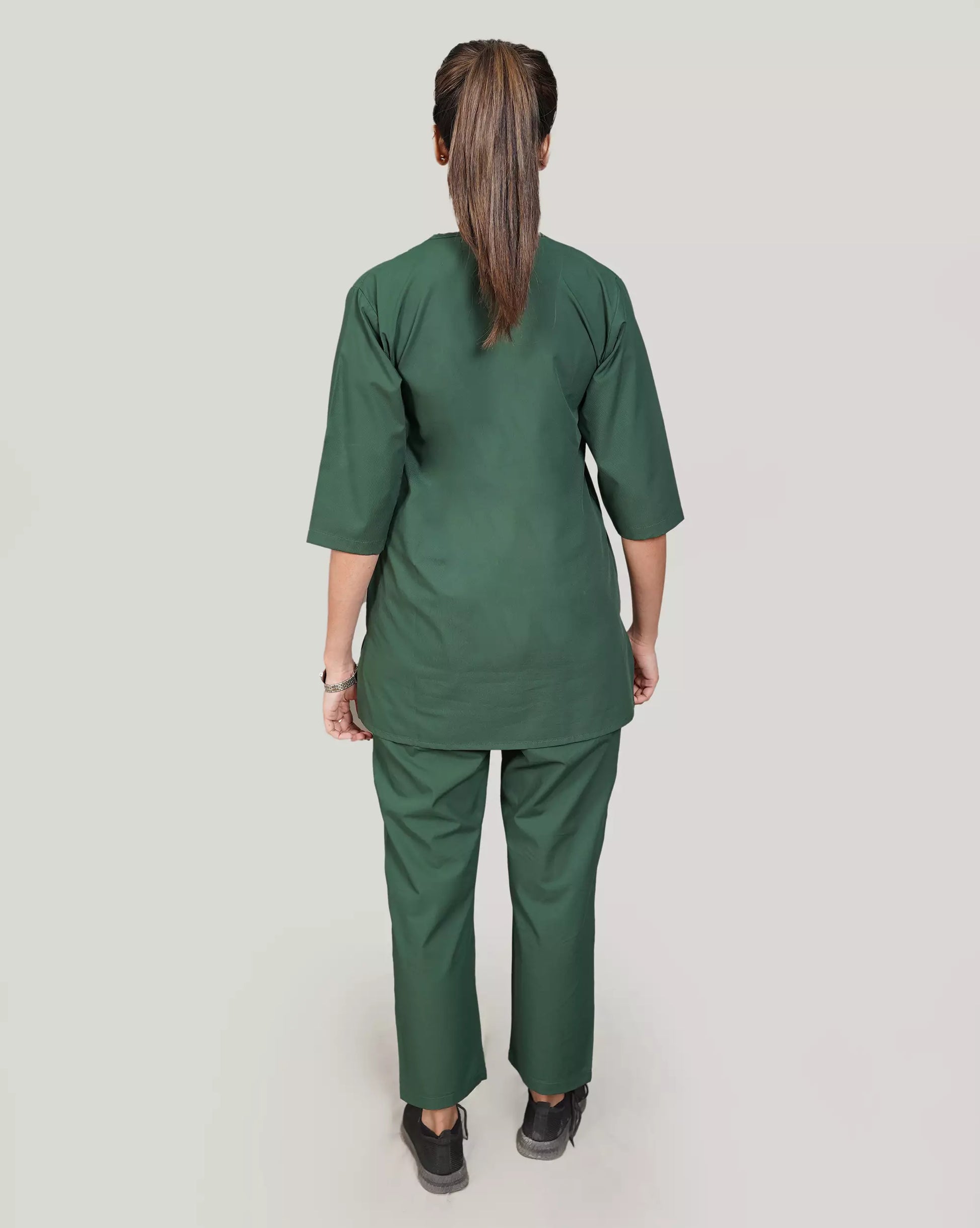 Person wearing a green medical scrub set on a plain background