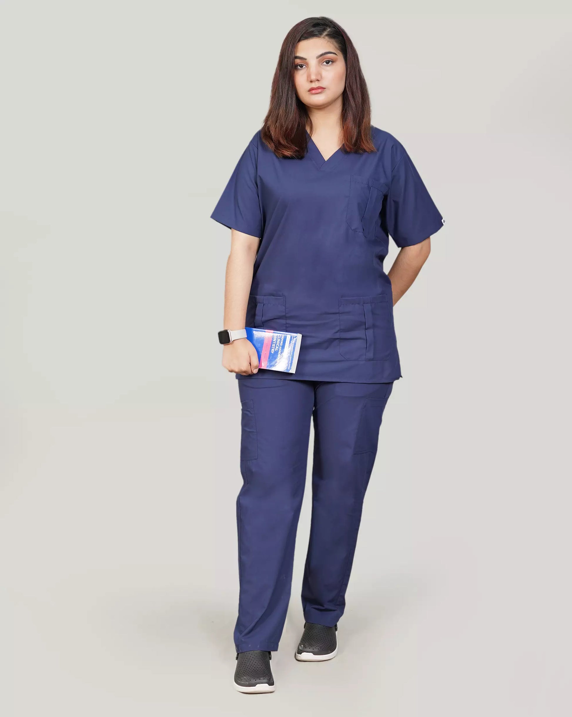 Full-body front view of a confident female medical professional in a complete navy blue Medfit unisex scrub set, holding a tablet, ideal for a professional and practical healthcare uniform.