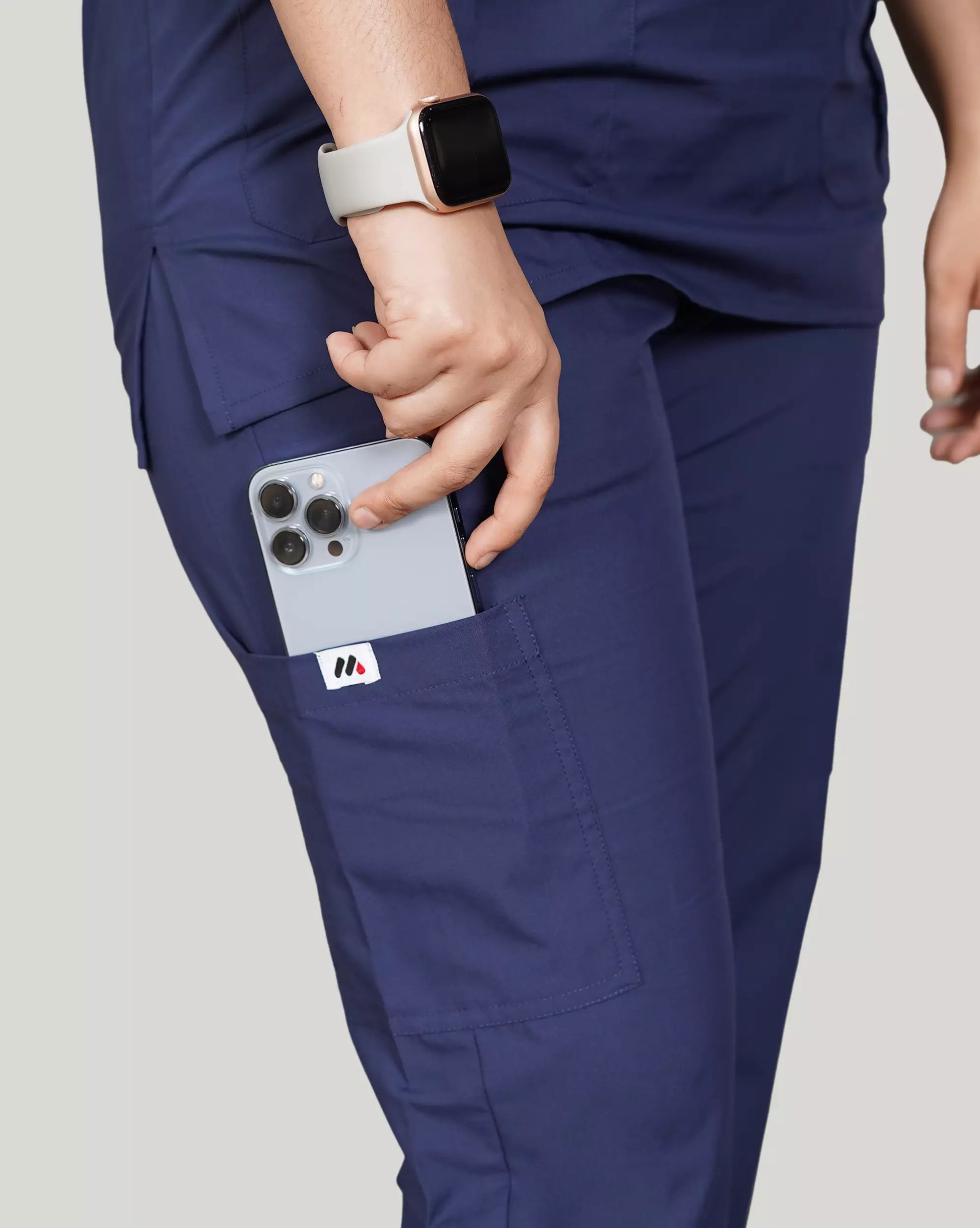 Full-body profile of a female medical professional in a sleek black Medfit unisex scrub set, featuring practical pockets and the Medfit logo on the leg for professional wear.