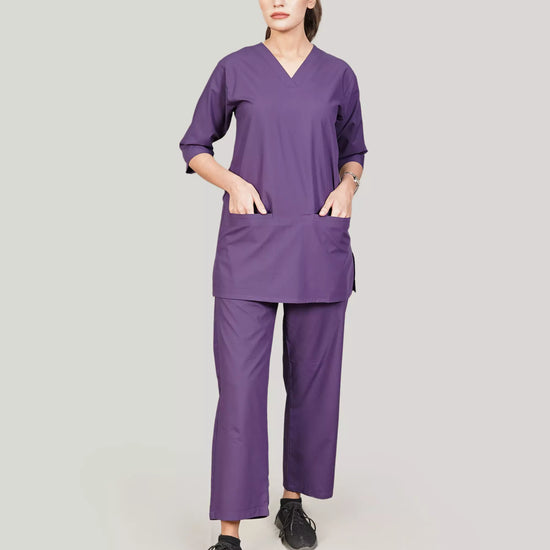 Person wearing a purple scrub set on a plain background