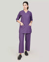 Person wearing a purple scrub set on a plain background