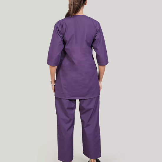 Person wearing a purple scrub set on a plain background