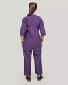 Person wearing a purple scrub set on a plain background