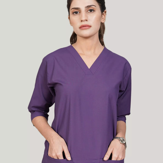 Woman wearing a purple scrub set on a plain background
