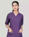 Woman wearing a purple scrub set on a plain background