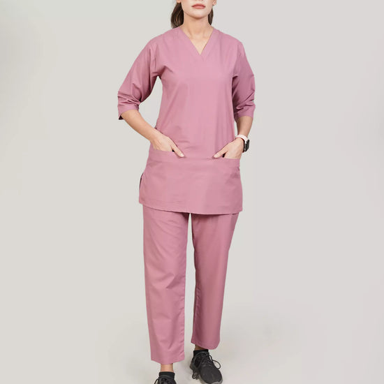 Person wearing a pink scrub set on a plain background