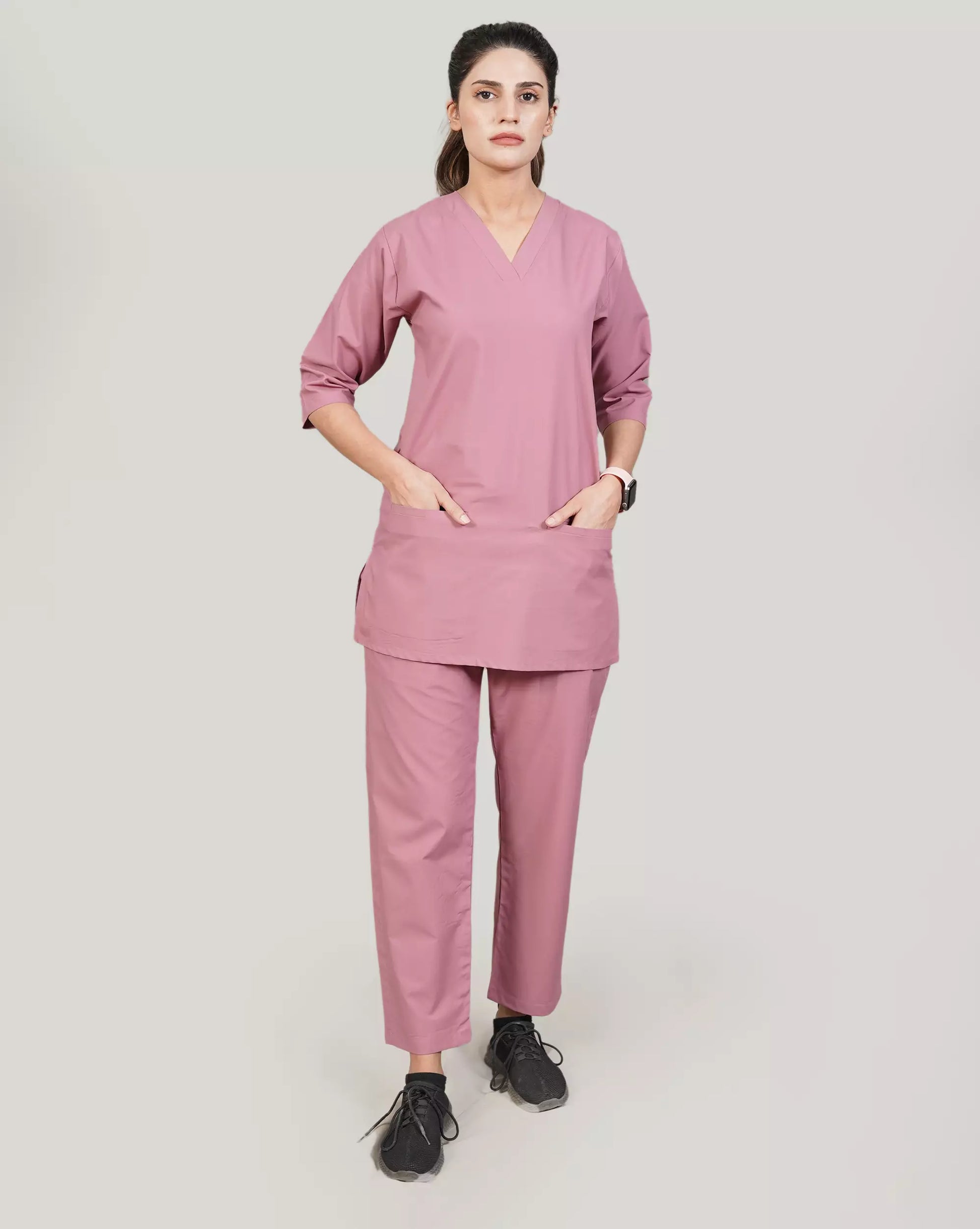 Person wearing a pink scrub set on a plain background