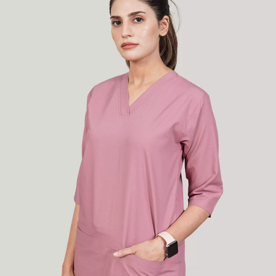 Woman wearing a pink scrub top with a plain background