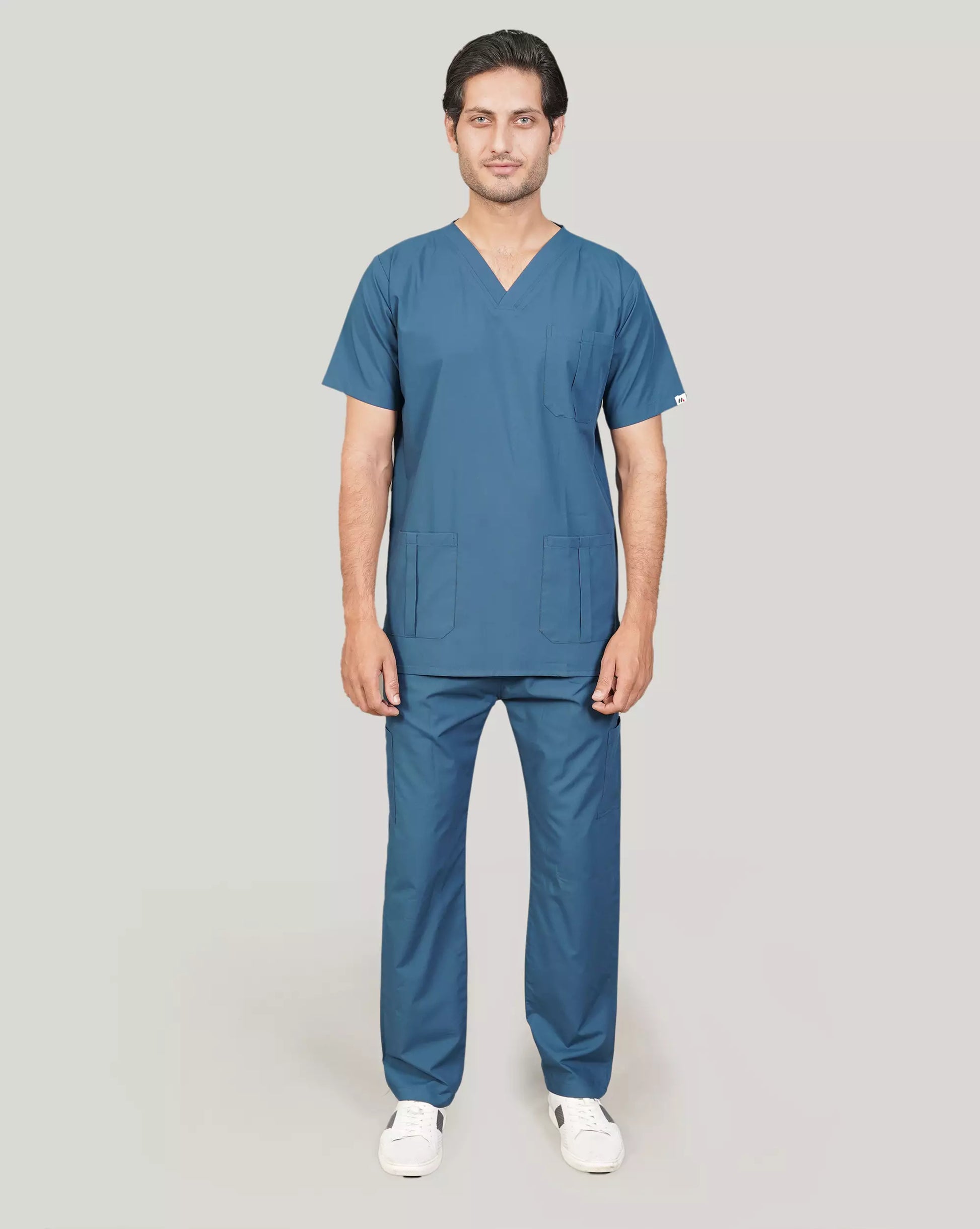 Smiling female healthcare professional wearing a full sage green Medfit scrub set with functional pockets, ideal for comfort and durability in medical settings.