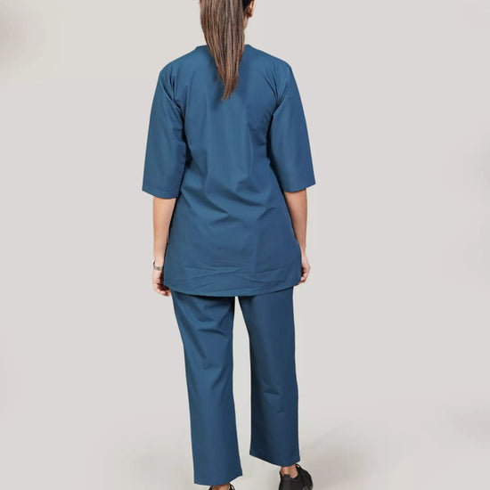 female doctor wearing a blue medical scrub set against a plain background