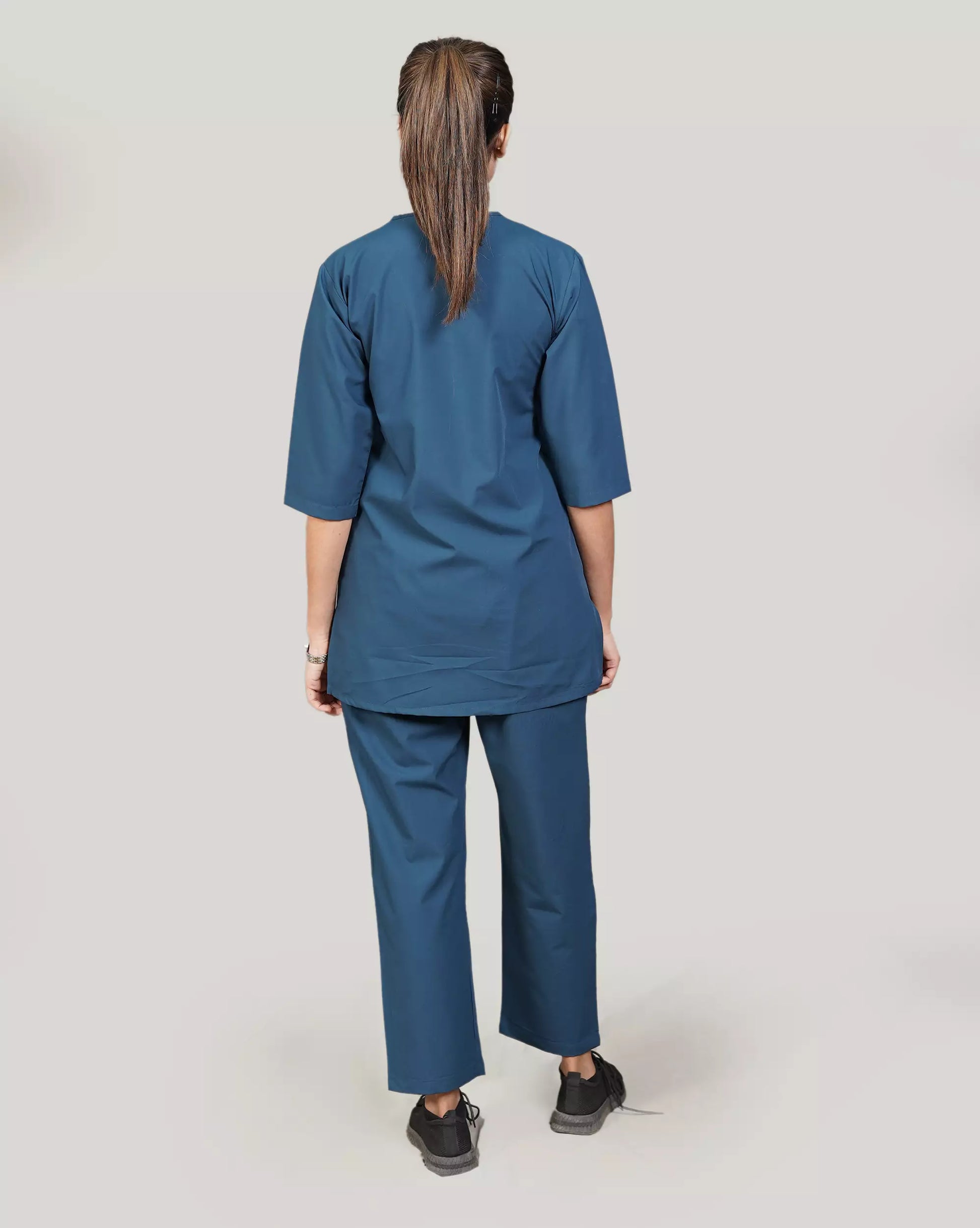 female doctor wearing a blue medical scrub set against a plain background