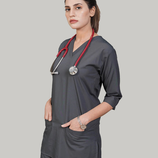 Woman wearing a gray scrub top with a red stethoscope on a plain background