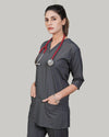 Woman wearing a gray scrub top with a red stethoscope on a plain background