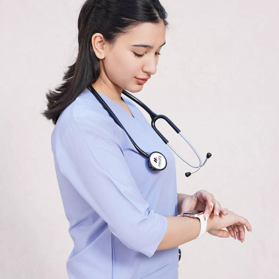 Healthcare professional in blue scrubs with stethoscope, checking wristwatch on white background.