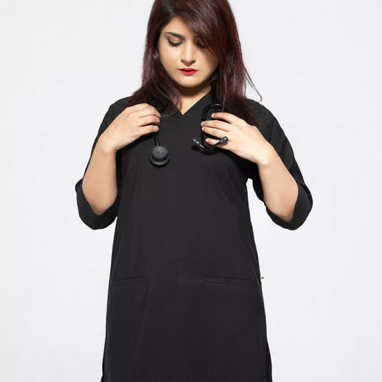 Woman wearing a black tunic scrub with a plain background