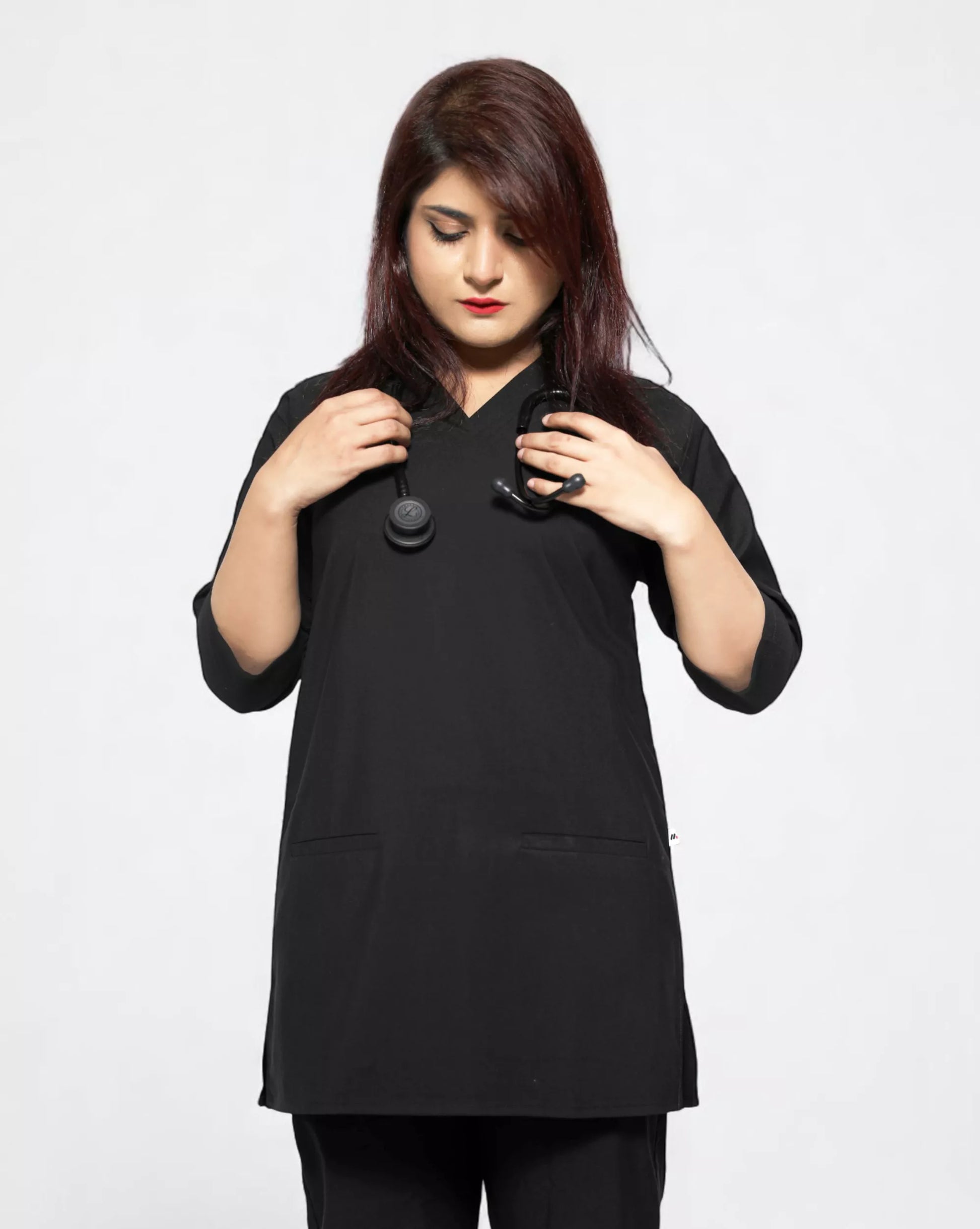 Woman wearing a black tunic scrub with a plain background