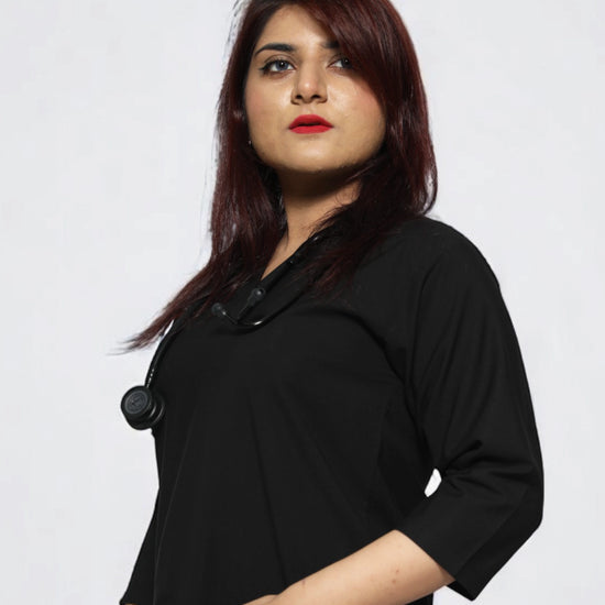 Person wearing a black scrub top with a plain background