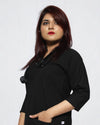 Person wearing a black scrub top with a plain background