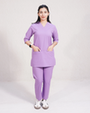 Person wearing a purple scrub set on a plain background