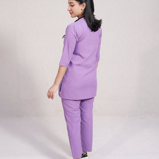 Person wearing a purple scrub set on a plain background