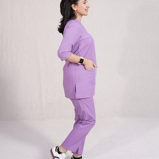 Person wearing a purple scrubs uniform set on a plain background