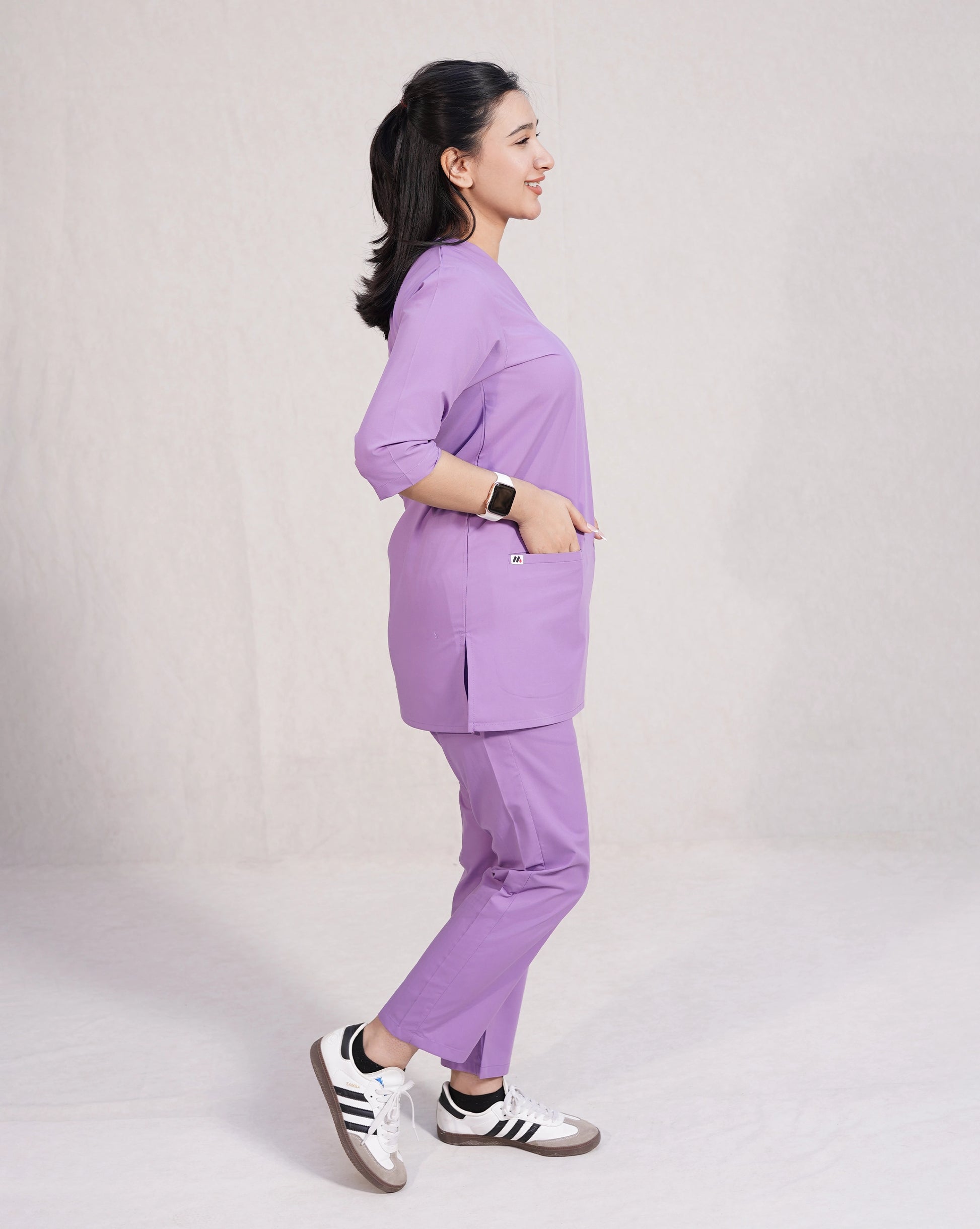 Person wearing a purple scrubs uniform set on a plain background