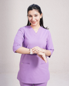 Person wearing purple medical scrubs on a plain background
